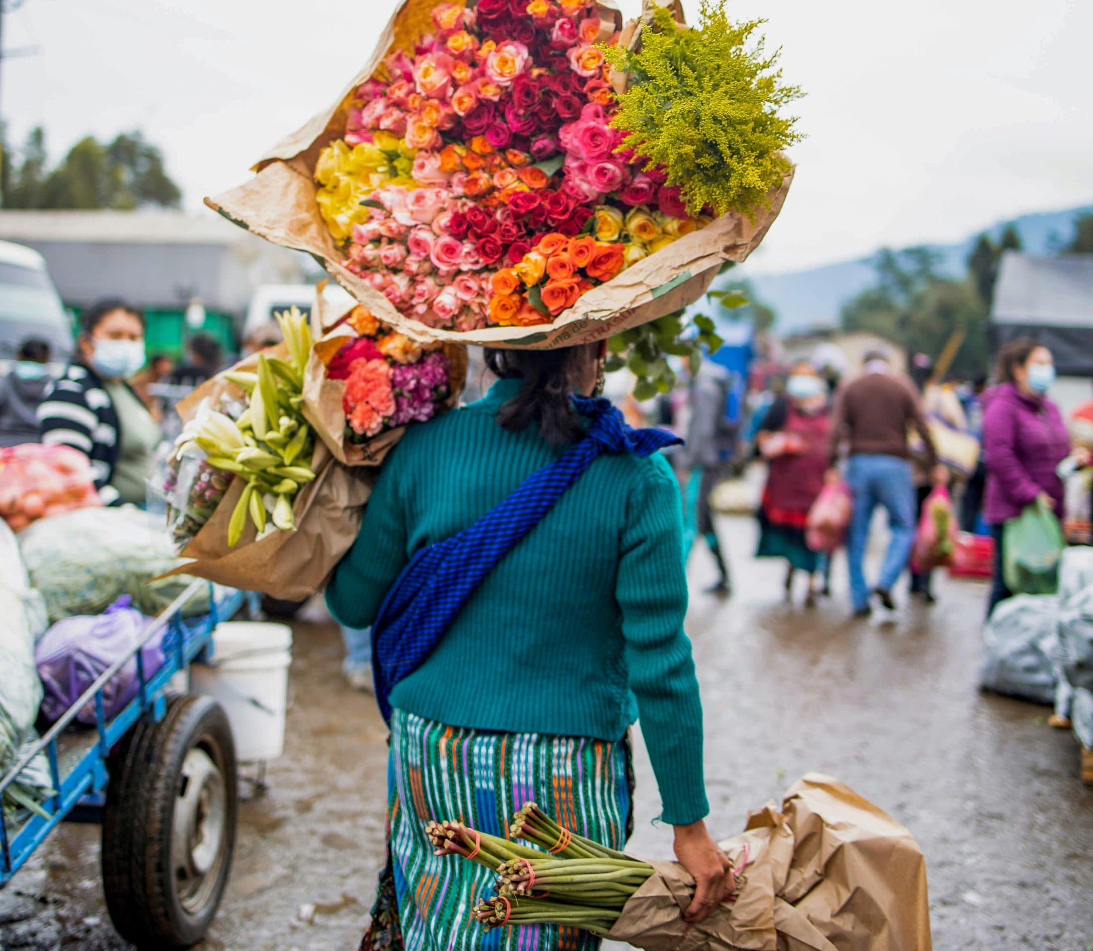 A flower vendor carries her goods through a market